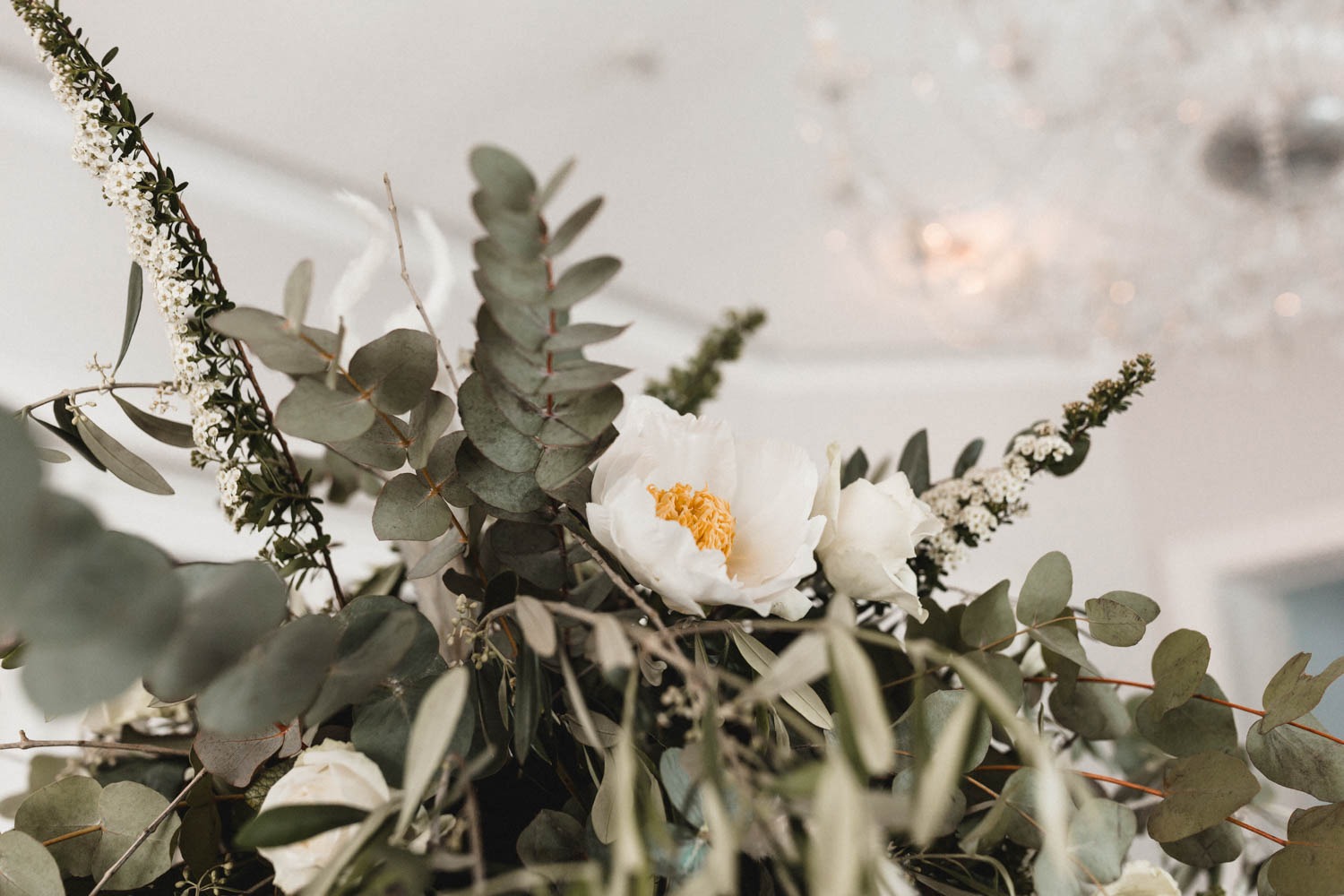 Geometrische Center Pieces mit Blumengesteck für Hochzeit mit viel grünen Elementen, wie Eukalyptus und Oliven, aus weißen, saisonalen Blüten (Pfingstrose und Rose) und getrocknetem Pampasgras
