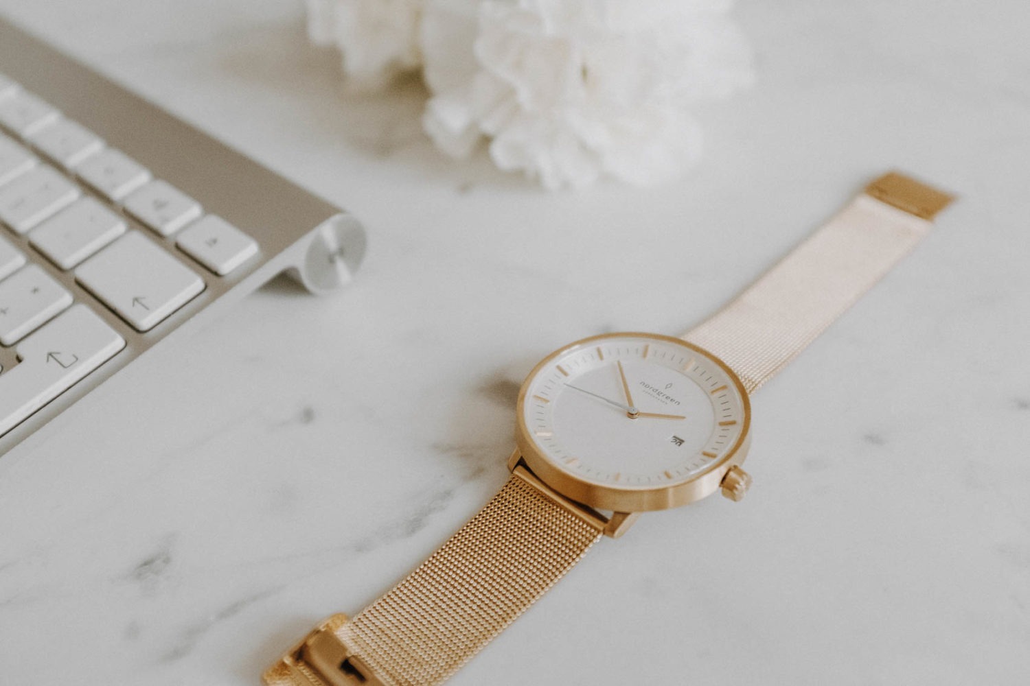 Marmor Schreibtisch mit Nordgreen Armbanduhr und Tastatur für erfolgreiches Pinterest Marketing