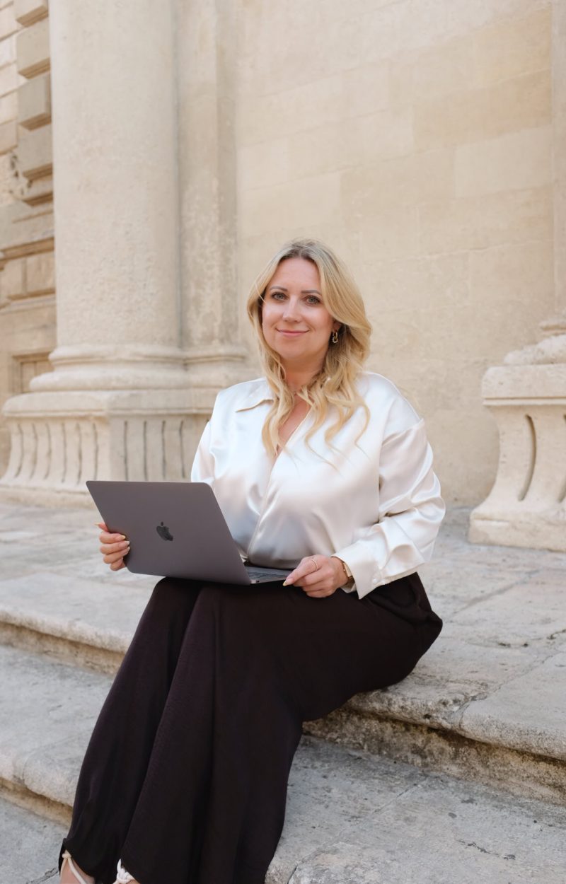 Authentische Businessfrau mit Laptop vor historischen Gebäuden in Berlin.