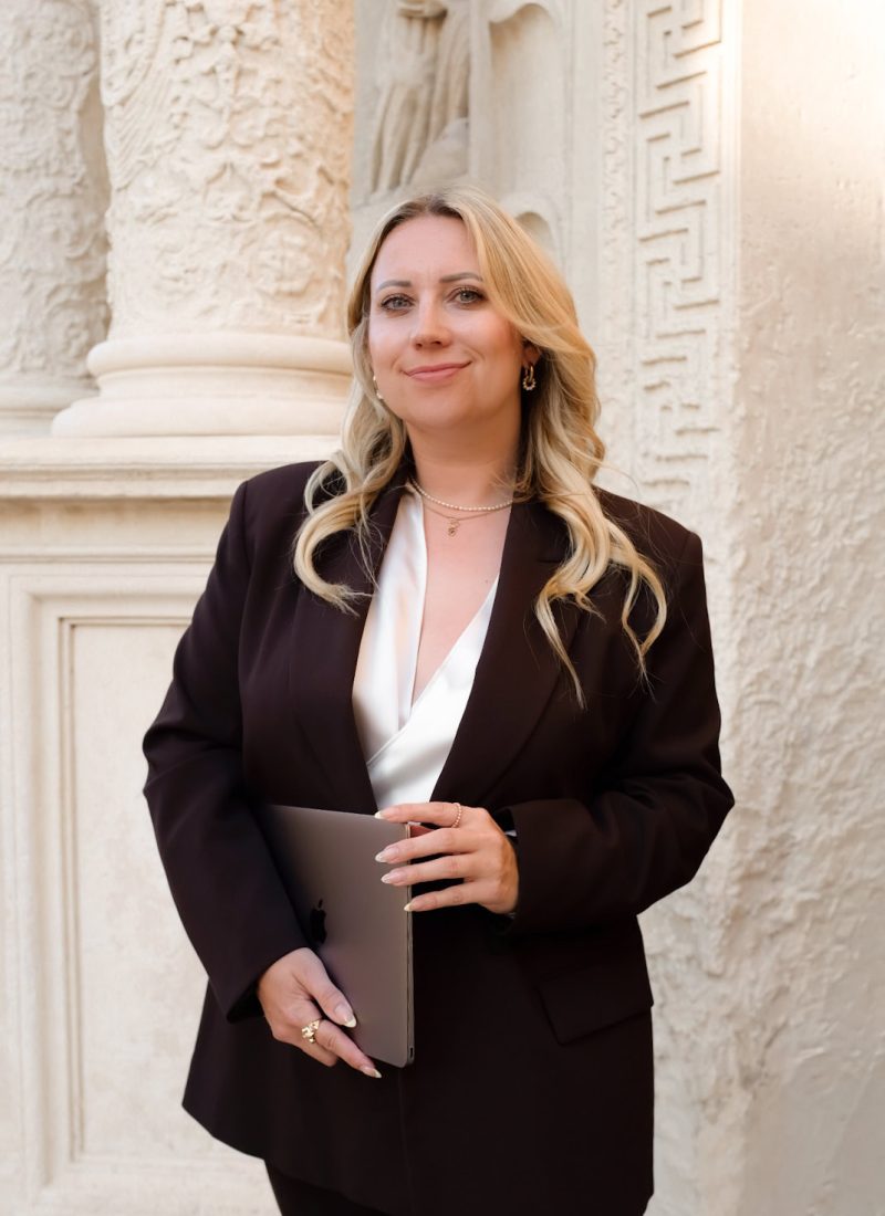 Hochwertiges Porträt von Alexandra Winzer vor antiker Architektur in eleganter Businesskleidung.