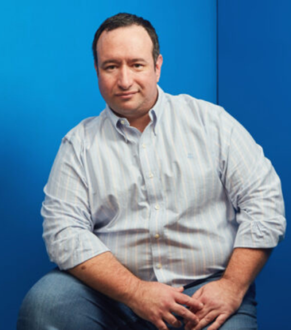 Professioneller Mann in Businesskleidung vor blauem Hintergrund.